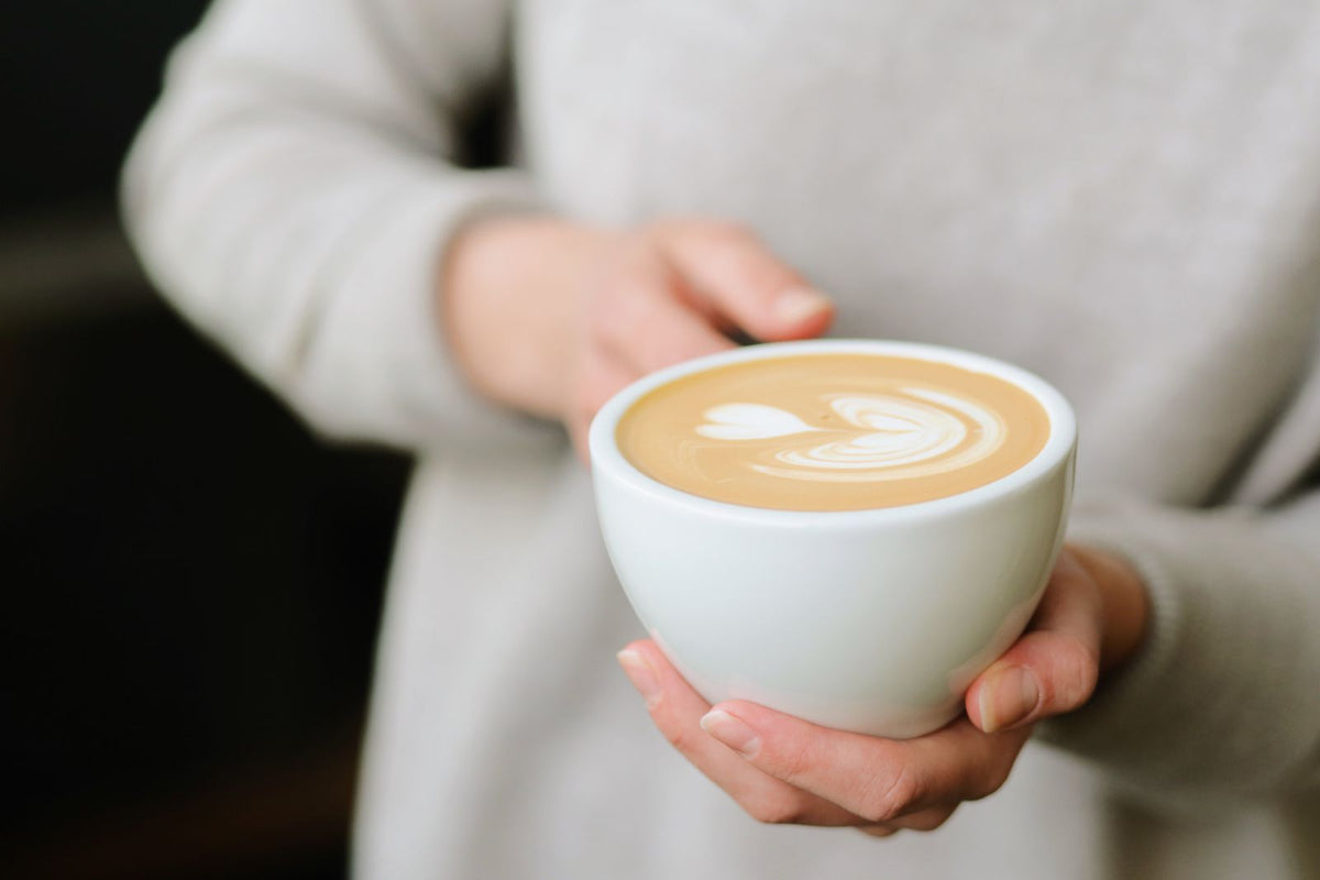 Hands holding a smooth latte with latte art